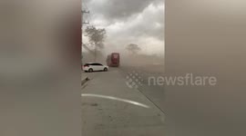Storm blows dust cloud reducing visibility on road in Thailand