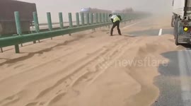 Police officer clears road with shovel as sandstorm halts traffic on Chinese highway