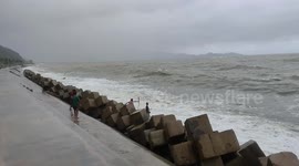 Youngsters play on breakwater amid rough waves from Typhoon Amang in the Philippines