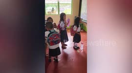 Stray dog sits in classroom while pupils sing song