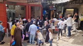 Christian worshippers wait behind a barrier set up by security forces barring the way to the Church of the Holy Sepulchre in Old Jerusalem, during the Orthodox Christian Easter Saturday celebrations