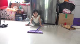 An 8 month old toddler does a wonderful job of brushing the floor, even though she is just learning to stand up.