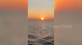 Spectacular moment sun sets on sea horizon as moon rises alongside