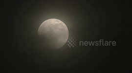Multiple time lapses of full moon Lunar eclipse with black inky clouds rolling across the moon's surface