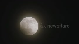 Multiple time lapses of full moon as spooky, inky black clouds roll across its surface