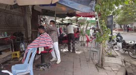 Barbers give open-air hair cuts on this street in Cambodia