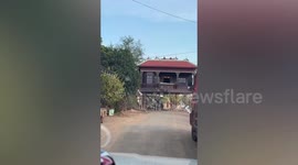House raised on stilts over rural road in Cambodia
