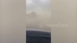 Storm blows dust cloud onto road reducing visibility in Thailand