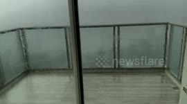 A wild and foggy rain thunderstorm in Thailand during the afternoon from inside of a high rise apartment with large windows. The rain was beating down hard on the balcony. It’s the first rainstorm in months and a total 180 from the Asia heatwave with litt