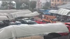 Twenty cars damaged as summer storm blows down tents in carpark in Thailand