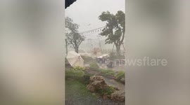 Severe hailstorm blows away garden umbrellas at art gallery in Thailand