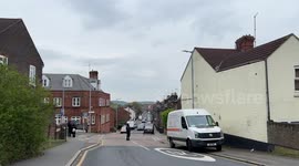 Street, people crossing, hill, cars , over cast, houses, neighbourhood