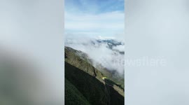Amazing athlete crosses over mountains balancing along springy slack line in Brazil