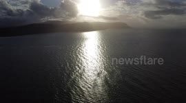 Drone view of glistening sea waves under the sun with welsh hills in the background on Llandudno east shore