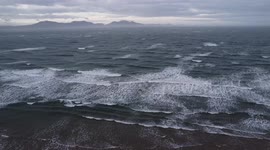 Drone view of moody looking sea waves on a windy day on a beach in Anglesey