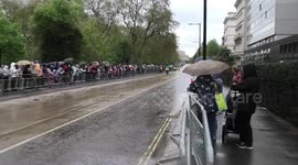 Coronation attendees cheer a police officer on a bicycle ad they wait for King Charles III