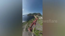 Awesome slackliner crosses rope across hilly beach in Brazil