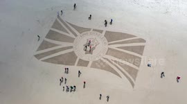 Giant Union Jack flag with silhouette of King Charles III etched on beach at Bamburgh Castle