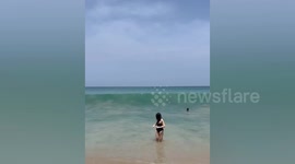 Woman flattened by wave while posing for photo on beach in Thailand
