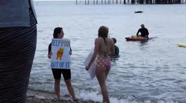 Surfers Against Sewage event on the beach 20th May 2023 showing woman activists holding up placards at the waterside on a sunny day in Brighton UK.