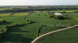 4K drone rotating flyover view of well presented farming fields and nearby village