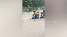Motorcycle riders struggle through flooded road amid monsoon rain in the Philippines