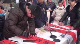 Children born in year of monkey use writing brush to write Spring Festival couplets and give them to citizens