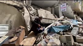Palestinian antique collector Hazem Muhanna, 62, holds old banknotes as he sits amidst the rubble of his house in Gaza City, which was destroyed in an Israeli air strike during the latest Israel-Gaza conflict