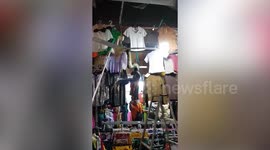 Huge python emerges among clothes on market stall in Cambodia