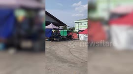 Rainbow-coloured umbrella flies into air as frantic street vendors fold their tents during windy weather