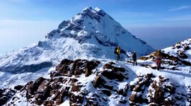 Toma aérea de alpinistas escalando el volcán Iliniza Norte y volcán Iliniza Sur detrás con drone en un día nevado