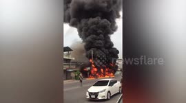 Black smoke plume rises from burning pick-up truck as fire spreads to wooden home
