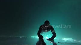 INCREDIBLE images and video footage has captured a brave diver swimming upside down under a layer of ice before diving into an underwater plane and a submarine wrecks – without any breathing equipment.