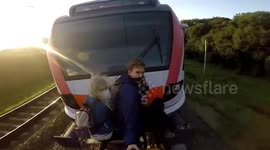 Daredevil teenager hangs dangerously from moving train as it reaches speeds of 75 miles per hour
