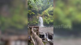 Soaked tourists rush to flee overflowing waterfall after sudden thunderstorm