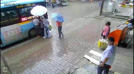 Woman selflessly shields elderly passengers with umbrella on rainy day commute