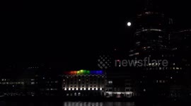 Full Moon Rises Over A Building lit up for Pride Month