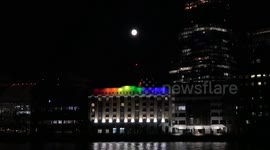 June Full Moon rises over building lit up for Pride Month in London