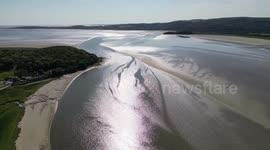 Stunning drone view of a sunset along Arnside beach bay and sand bars with the rail bridge and Arnside village in view