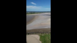 Portrait drone shot of Arnside Bay estuary, floating along the beach and with a sunset in view