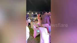 Wedding guest rolls on floor laughing as she falls off chair while twerking