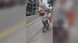 Woman rides bike while carrying three pet dogs