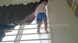 Playful one-year-old girl from Malaysia climbs up windows enclosure