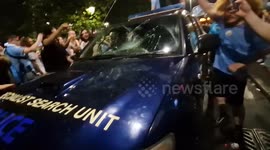 Man City fans bounce up and down on top of police car in city centre