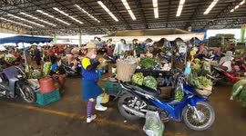 Energetic market vendor amuses customers with wacky dance while peeling coconuts