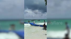 Couple fall on their backsides while crossing floating dock in choppy sea