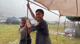 Festival-goers battle to hold up marquee being battered by storm in Thailand