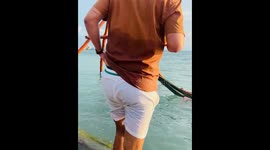 Man Slips and Falls in Ocean With His Drink