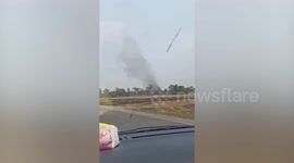 Moving dust devil tornado crosses road in front of drivers Thailand