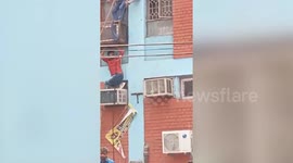 People escape by climbing down ropes as fire breaks out at the Coaching Institute in Mukherjee Nagar, Delhi, India